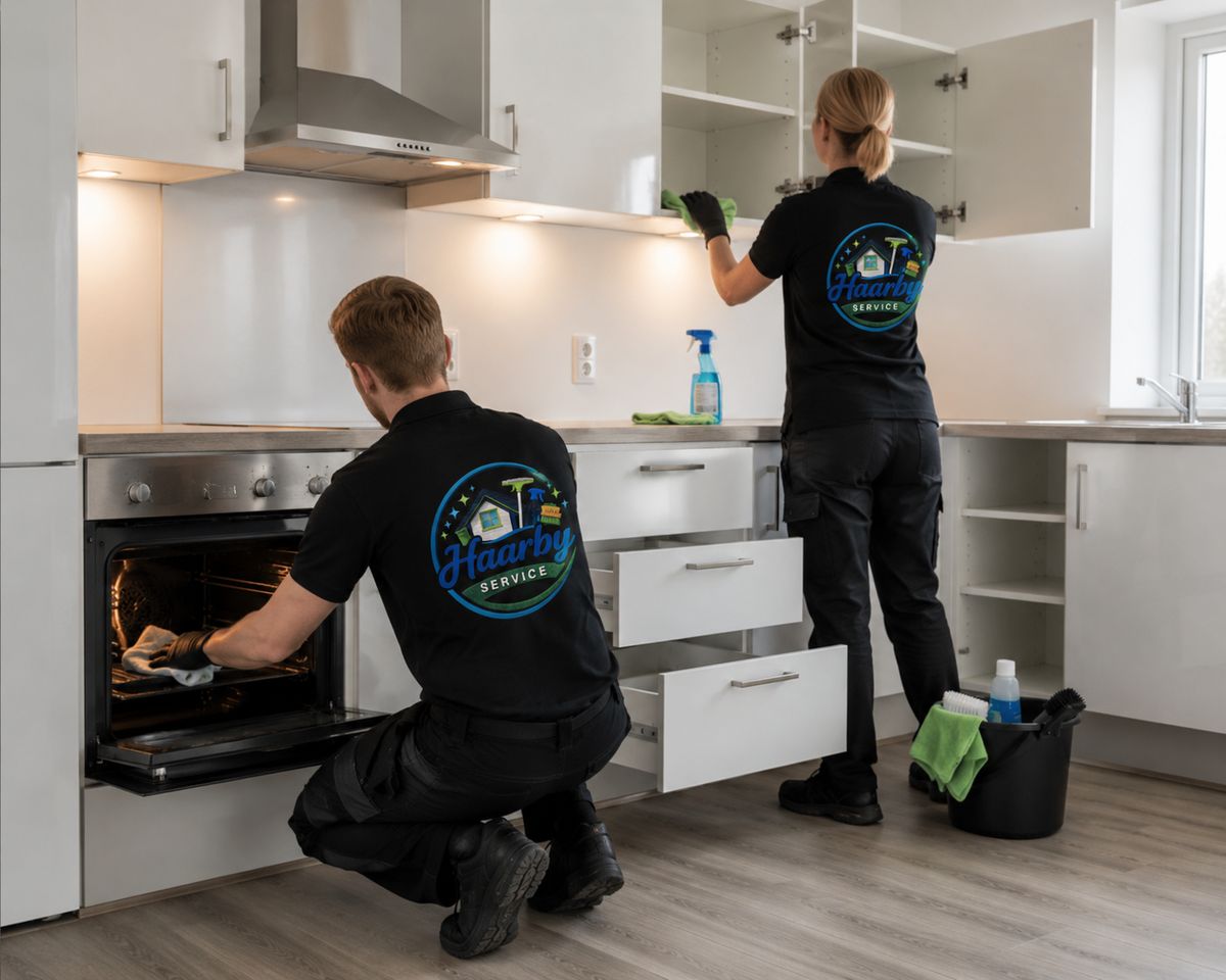 To rengøringsassistenter udfører grundig rengøring af hvidt køkken og ovn