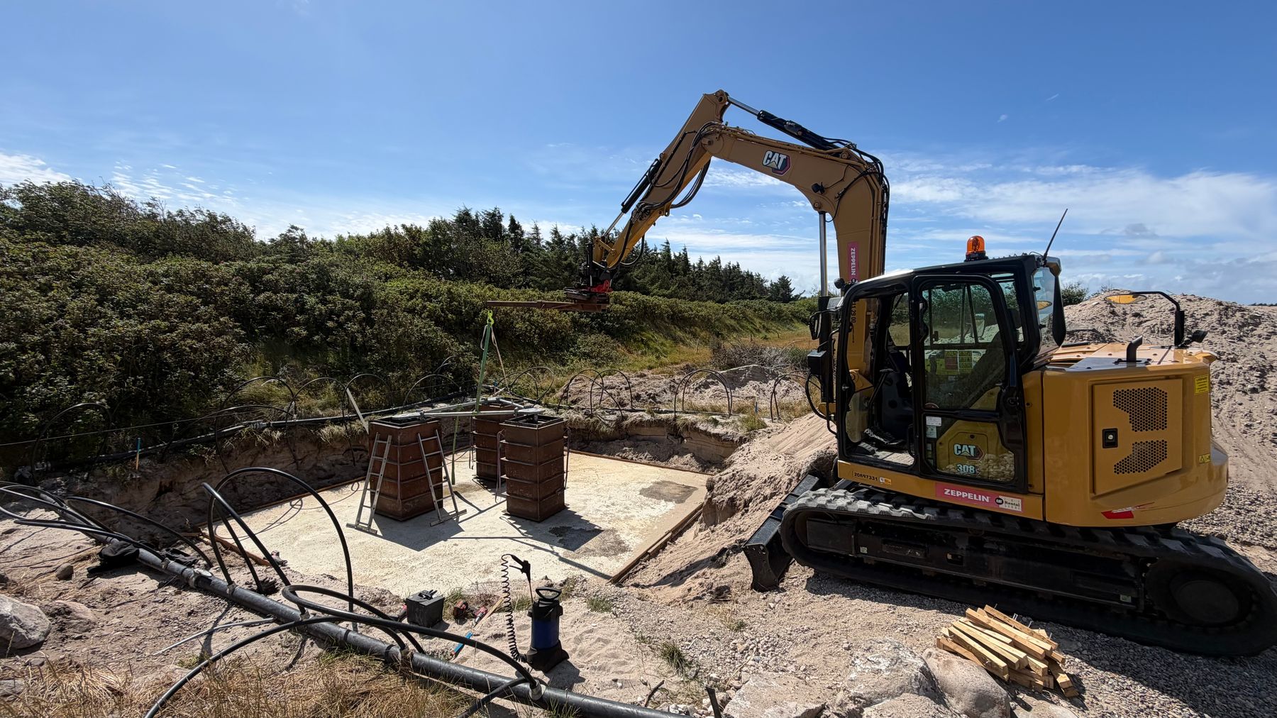 Gul CAT gravemaskine ved udgravning af rende til fundament og sokkel