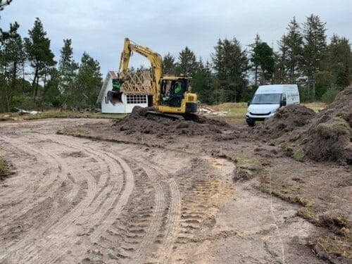 Gravemaskine udfører nedbrydnings- og jordarbejde på byggeplads