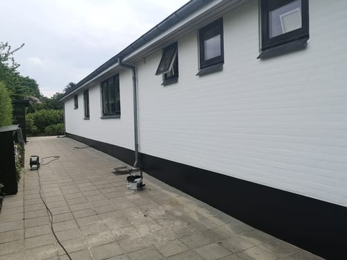 Nymalet hvid murstensfacade med sorte detaljer