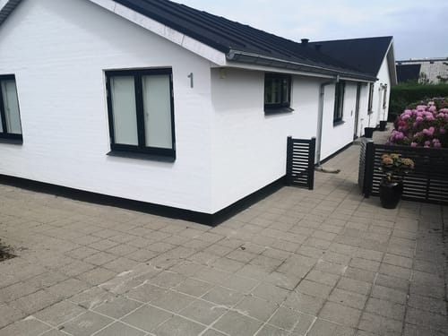 Hvidt etplanshus med sort tag og terrasse