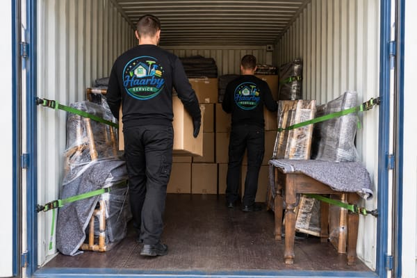 Flyttemænd pakker og fastspænder flyttekasser og beskyttede møbler i container