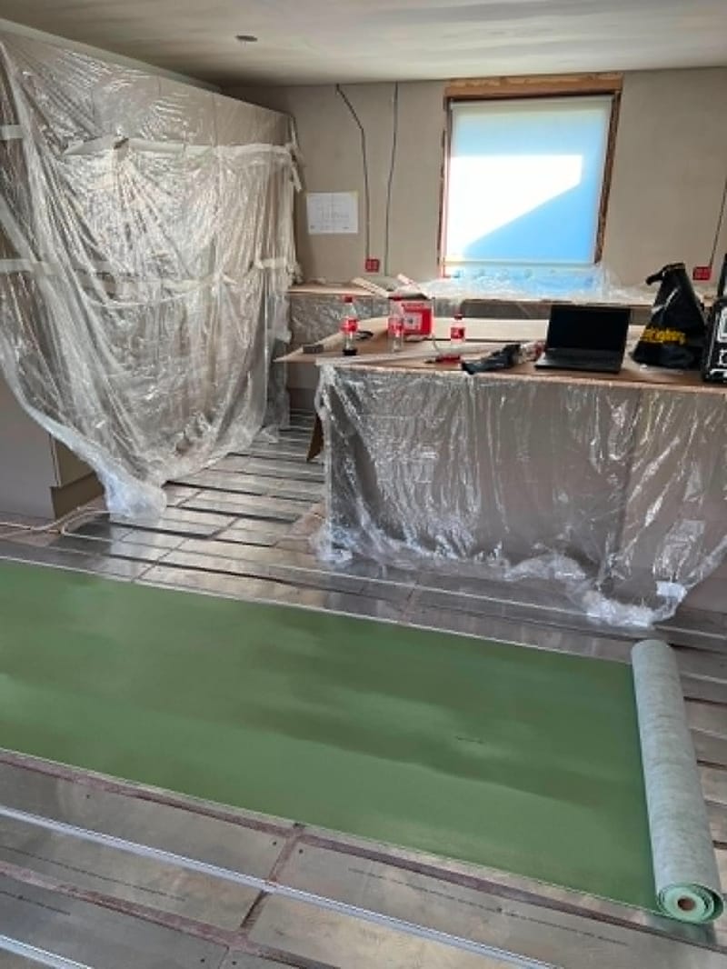 Etablering af nyt gulvlag og professionel afdækning – Indvendigt gulvarbejde. Rummet er afdækket med plast, og et nyt gulvlag er ved at blive etableret.