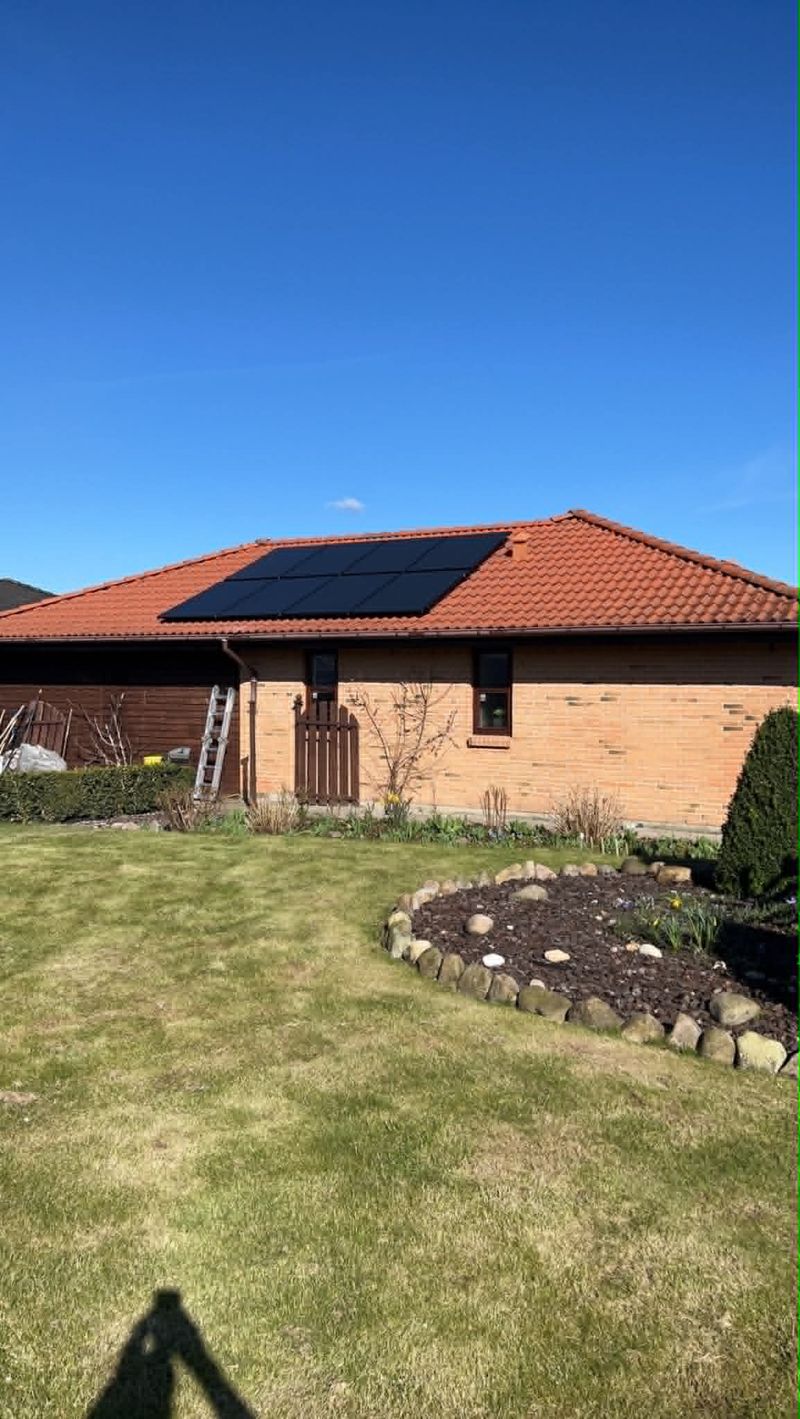 Færdigt rødt tegltag med monterede solceller – Færdigt parcelhus med rødt tegltag og solcellepaneler monteret på taget.