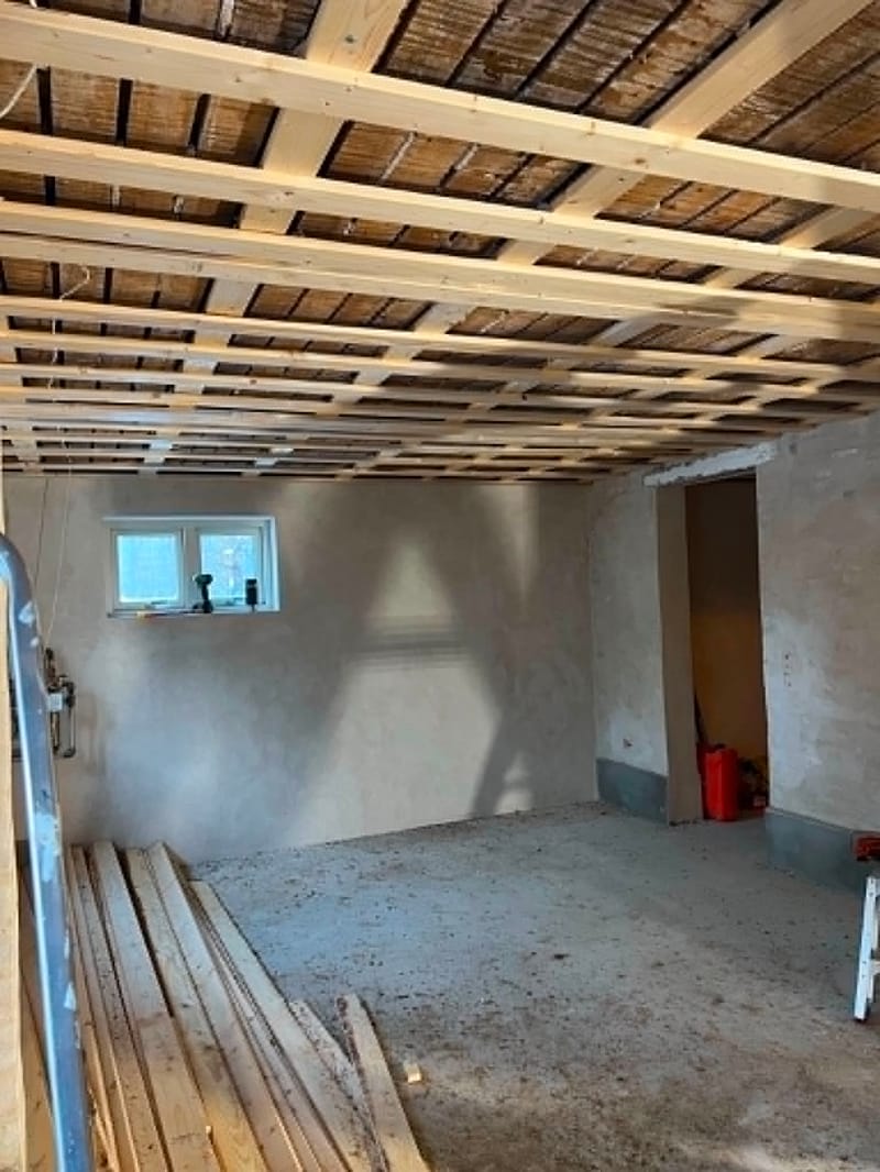 Totalrenovering med fritlagte loftsbjælker – Indvendig totalrenovering med synlige loftsbjælker og rå vægge/gulve. Rummet er klar til videre opbygning.