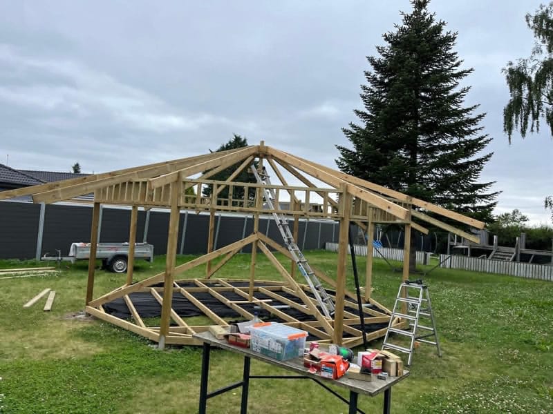 Ny trækonstruktion med spær og stolper til overdækning – Ny trækonstruktion til en tilbygning, terrasseoverdækning eller lignende er ved at blive opført. Spær og stolper er monteret.
