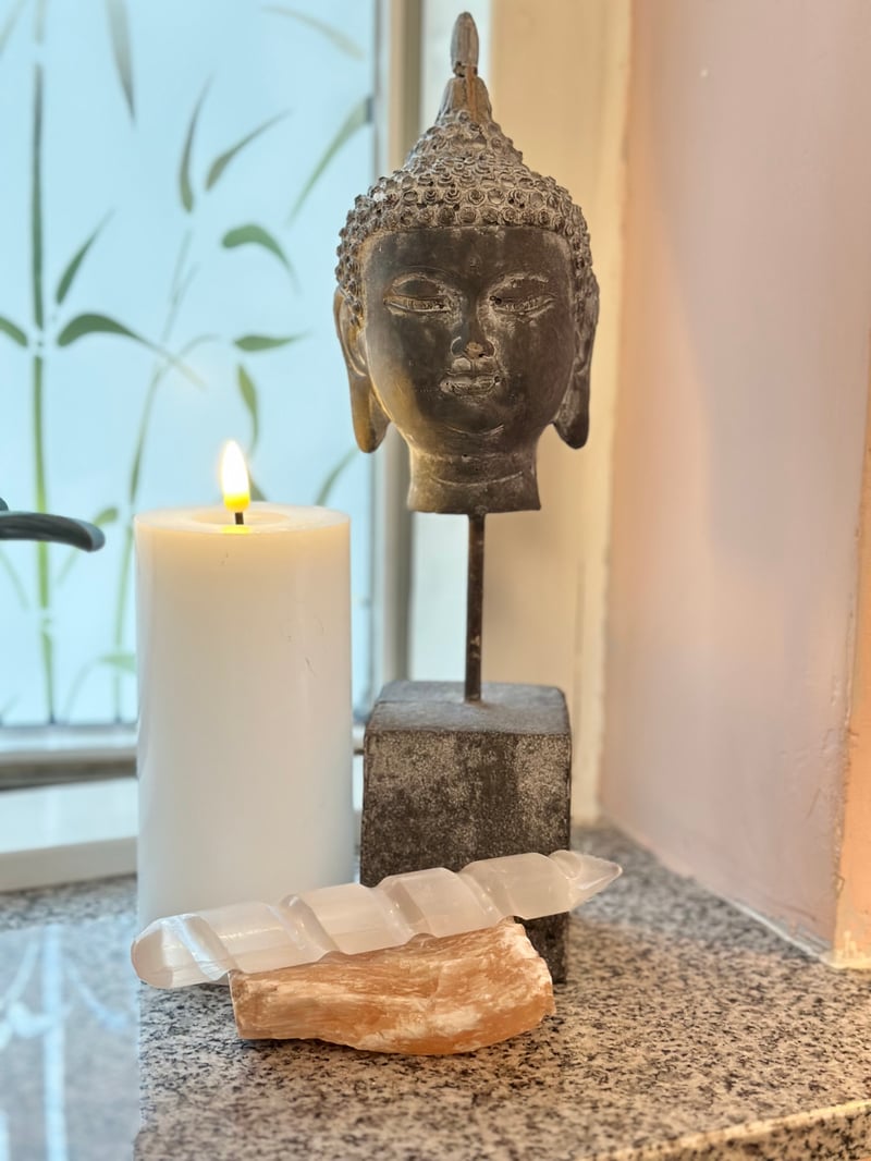 Buddha-figur, tændt bloklys og krystaller hos Klinik Ro og Velvære