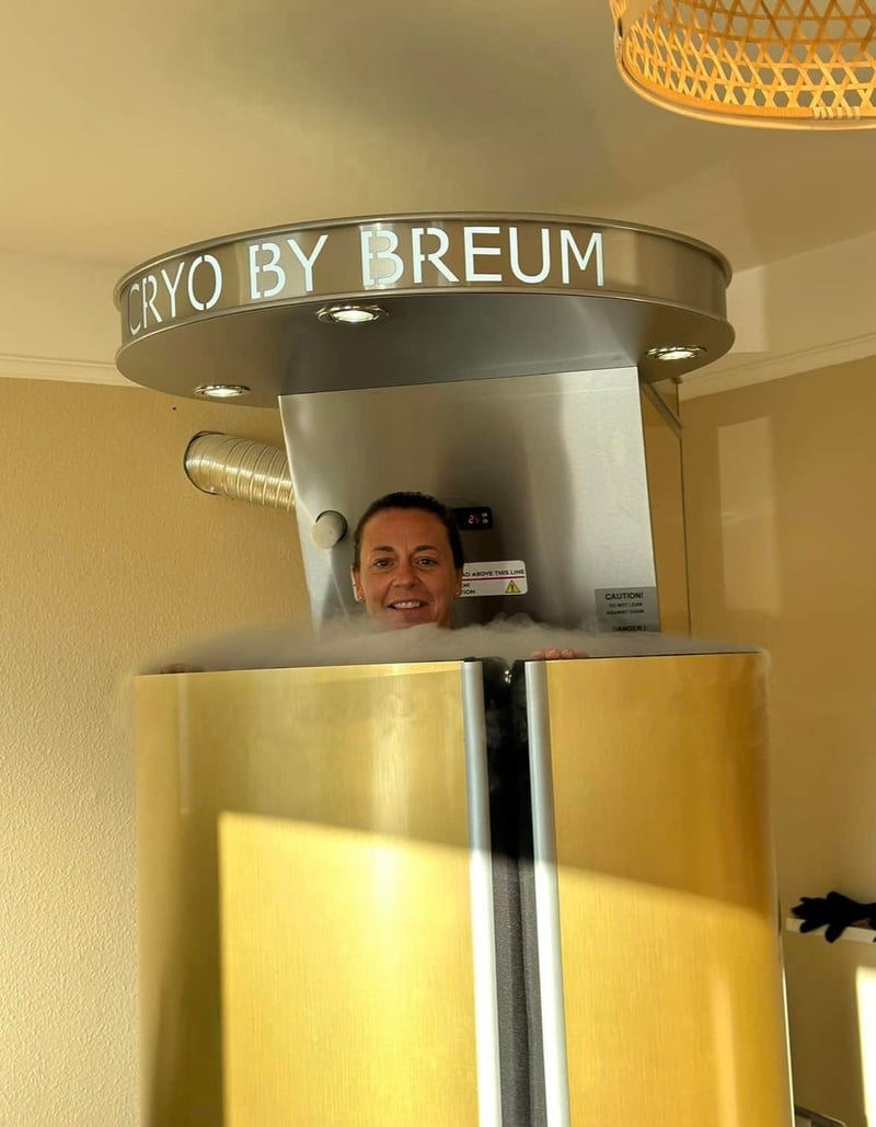 Kvinde under opkvikkende kryoterapibehandling i gylden kryokabine hos Cryo by Breum